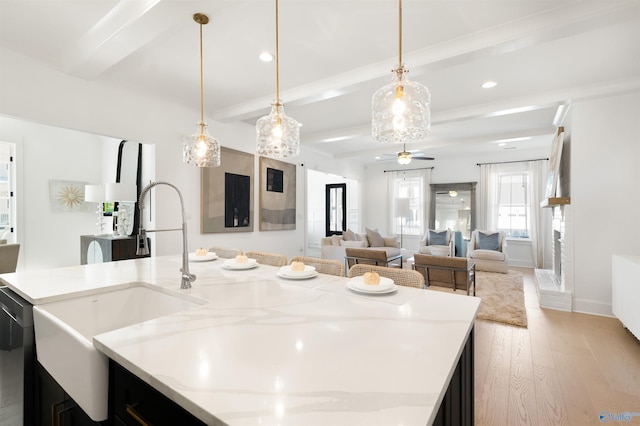 kitchen featuring light stone counters, hanging light fixtures, and beamed ceiling