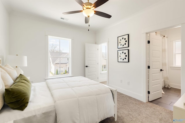 bedroom with light colored carpet, ensuite bath, ornamental molding, and ceiling fan