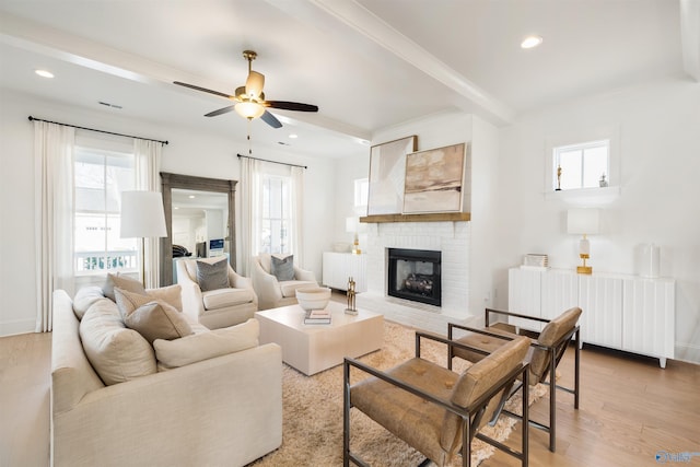 living room with light hardwood / wood-style flooring, radiator, beamed ceiling, ceiling fan, and a fireplace