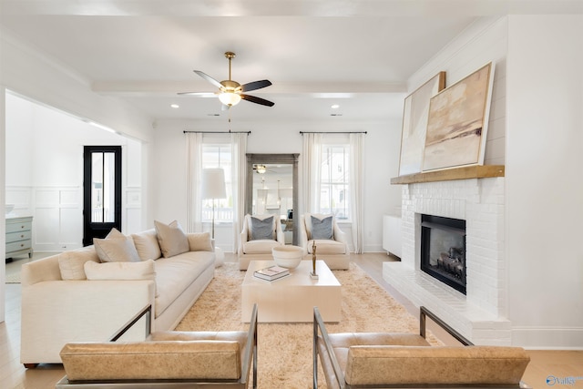 living room featuring light hardwood / wood-style flooring, beam ceiling, a fireplace, and ceiling fan