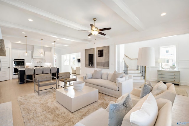 living room with ceiling fan, light wood-type flooring, and beam ceiling