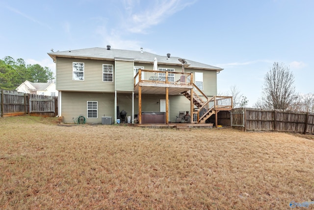 rear view of property featuring a lawn, central AC, a hot tub, and a deck