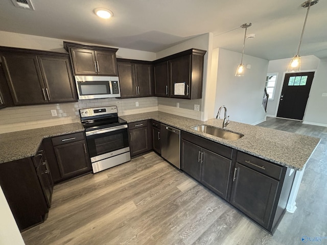 209 Roman Randall Rd, New Market, AL 35761 - kitchen with dark stone countertops, a peninsula, appliances with stainless steel finishes, light wood finished floors, and a sink