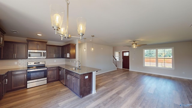 209 Roman Randall Rd, New Market, AL 35761 - kitchen with light wood-type flooring, appliances with stainless steel finishes, a peninsula, light stone countertops, and decorative backsplash