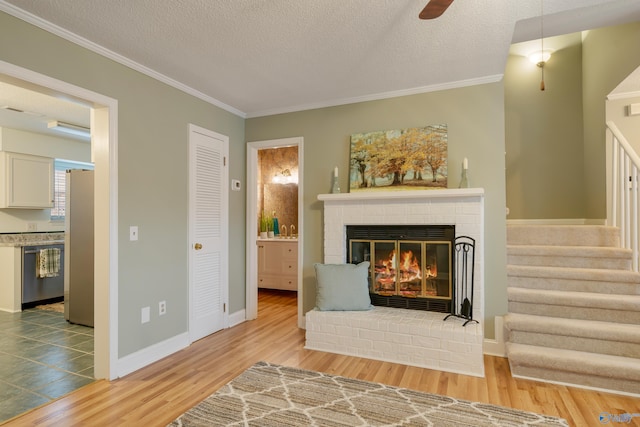 living area with wood-type flooring, ornamental molding, and a textured ceiling