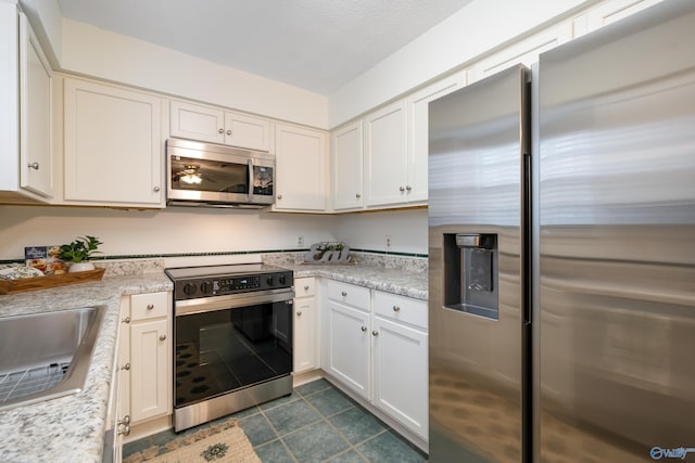 kitchen featuring stainless steel appliances, light stone countertops, and white cabinetry