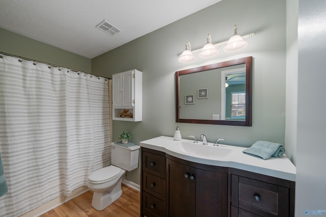 bathroom with vanity, a textured ceiling, hardwood / wood-style flooring, curtained shower, and toilet