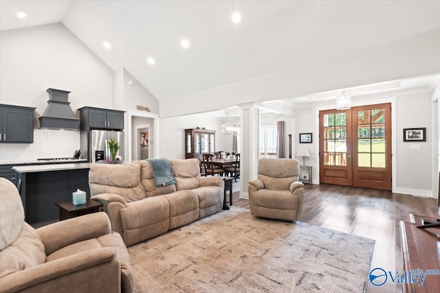 living room featuring an inviting chandelier, a wealth of natural light, decorative columns, and wood-type flooring