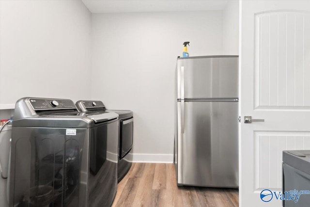 washroom with washing machine and dryer and light hardwood / wood-style floors