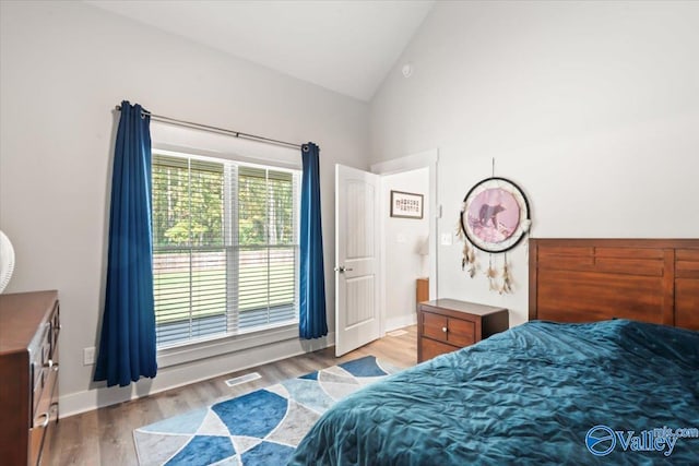 bedroom with light wood-type flooring and high vaulted ceiling