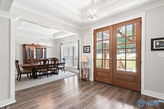 foyer featuring dark hardwood / wood-style floors, a raised ceiling, an inviting chandelier, and french doors