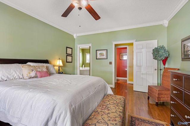 bedroom with a ceiling fan, wood finished floors, baseboards, ensuite bathroom, and crown molding