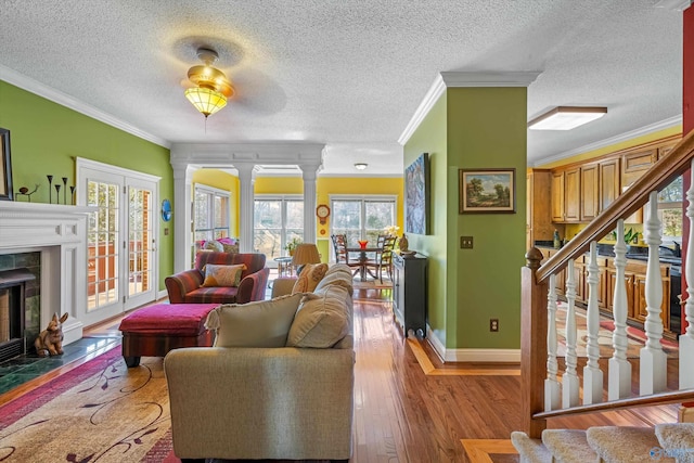 living room featuring baseboards, a tiled fireplace, stairway, ornamental molding, and hardwood / wood-style floors