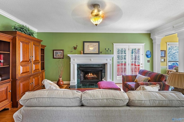 living area featuring a ceiling fan, a textured ceiling, wood finished floors, a fireplace, and crown molding