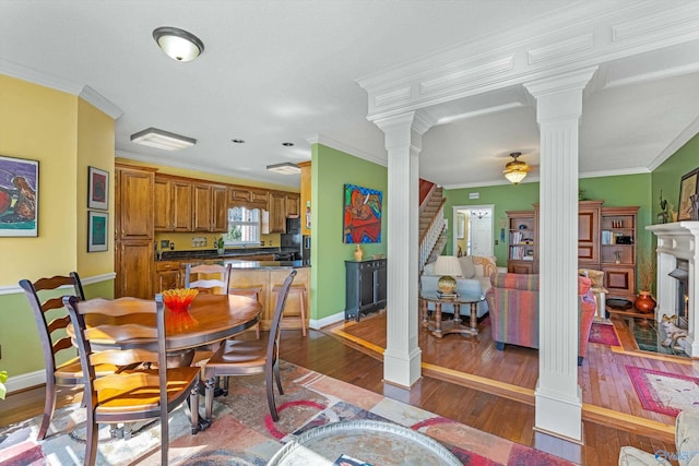 dining room featuring baseboards, stairway, ornamental molding, hardwood / wood-style floors, and decorative columns