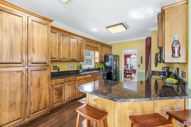 kitchen with a breakfast bar area, fridge with ice dispenser, ornamental molding, a peninsula, and dark wood-style flooring