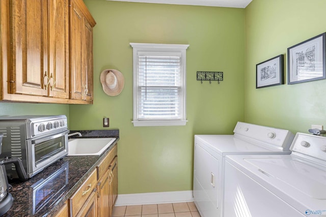 washroom featuring washing machine and clothes dryer, baseboards, a toaster, light tile patterned floors, and a sink