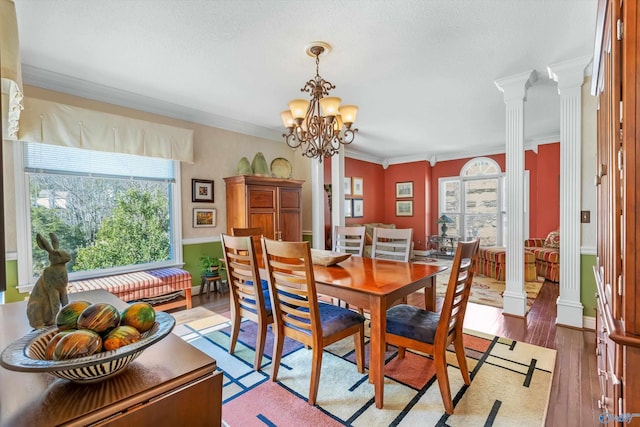 dining area with ornamental molding, light wood-style floors, decorative columns, baseboards, and a chandelier