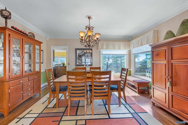 dining space featuring a textured ceiling, an inviting chandelier, wood finished floors, and crown molding