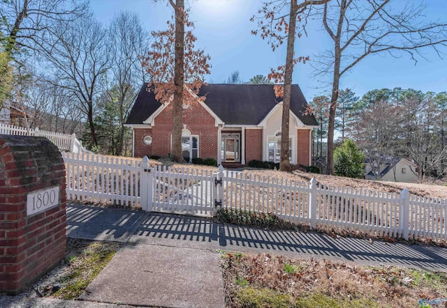 view of front of home featuring a gate, a fenced front yard, brick siding, and a shingled roof