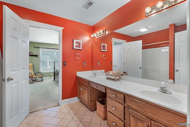 bathroom featuring a sink, visible vents, double vanity, and tile patterned flooring