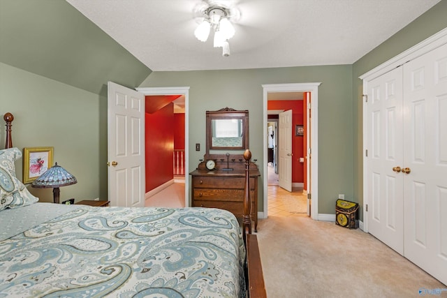 bedroom with baseboards, lofted ceiling, ceiling fan, a closet, and light carpet