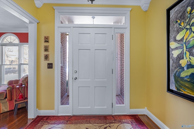 foyer entrance with wood finished floors, baseboards, and ornamental molding