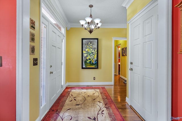 foyer entrance featuring baseboards, crown molding, an inviting chandelier, and wood finished floors