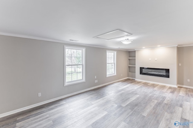 unfurnished living room featuring visible vents, baseboards, ornamental molding, light wood-style floors, and a glass covered fireplace
