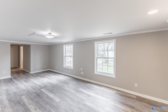 spare room with crown molding, wood finished floors, visible vents, and baseboards