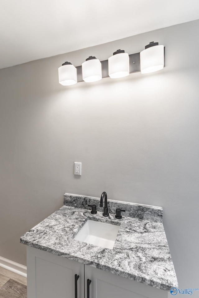 bathroom with baseboards, wood finished floors, and vanity
