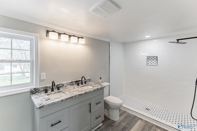 full bathroom with toilet, plenty of natural light, wood finished floors, and a tile shower