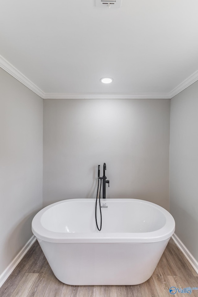 full bath with wood finished floors, recessed lighting, crown molding, baseboards, and a soaking tub