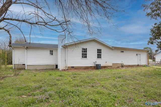 back of house featuring crawl space, central air condition unit, a yard, and a chimney