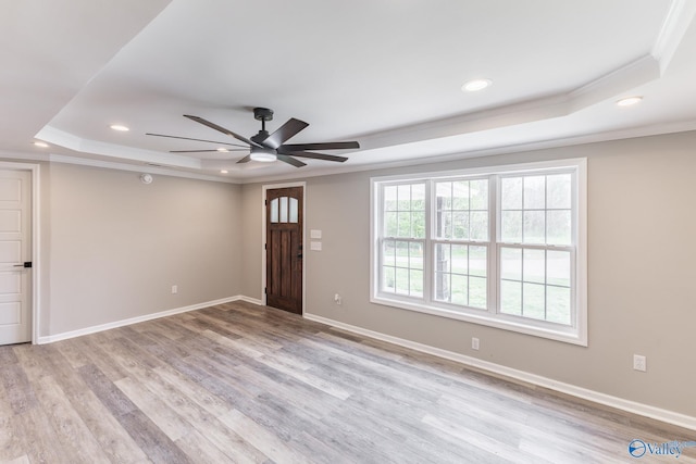 foyer entrance featuring baseboards, ornamental molding, recessed lighting, light wood-style flooring, and a raised ceiling