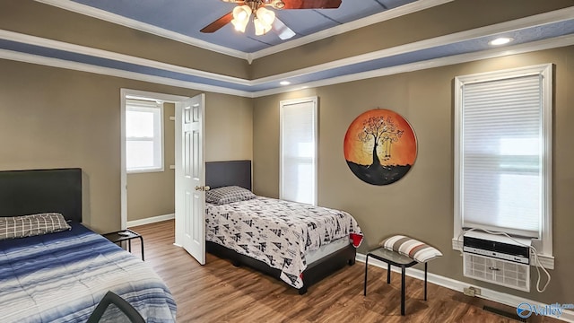 bedroom with hardwood / wood-style floors, a tray ceiling, ornamental molding, and ceiling fan