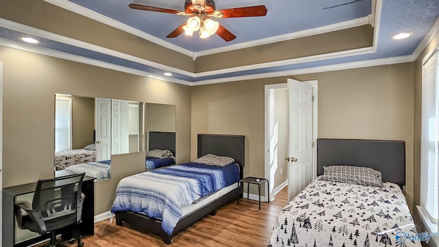 bedroom with crown molding, ceiling fan, a tray ceiling, and hardwood / wood-style flooring