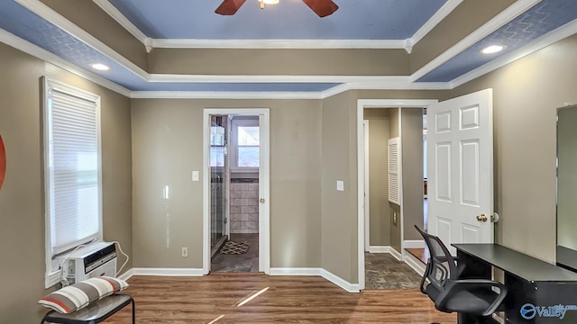 office space featuring a raised ceiling, ornamental molding, wood-type flooring, and ceiling fan