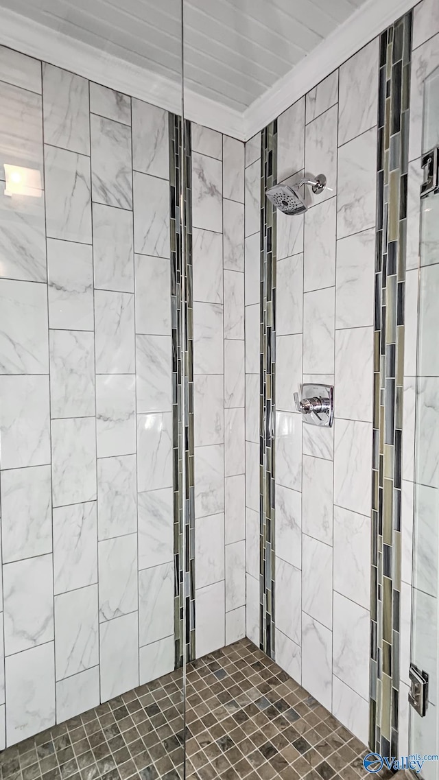 bathroom with crown molding and tiled shower