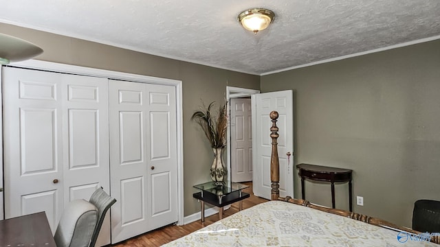 bedroom with ornamental molding, hardwood / wood-style floors, a textured ceiling, and a closet