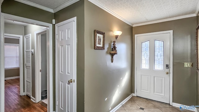 tiled entryway with ornamental molding and a textured ceiling