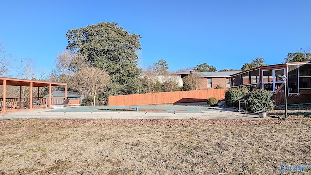 view of yard featuring a patio, a sunroom, and a covered pool