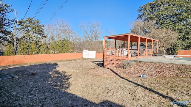 view of yard with a storage shed, a wooden deck, and a patio area