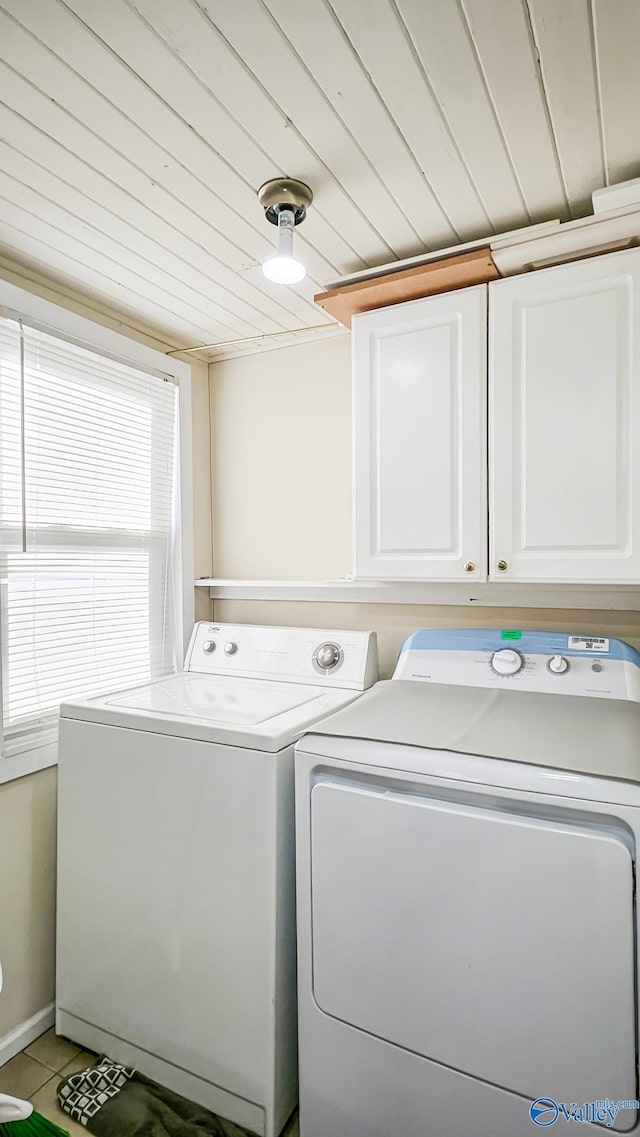 laundry area with tile patterned flooring, wood ceiling, washing machine and dryer, and cabinets