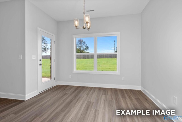 unfurnished dining area featuring a chandelier, a healthy amount of sunlight, and hardwood / wood-style flooring