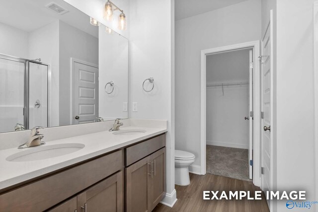 bathroom with wood-type flooring, vanity, toilet, and an enclosed shower