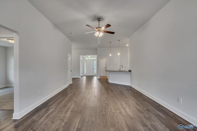 unfurnished living room featuring ceiling fan, sink, and dark hardwood / wood-style flooring