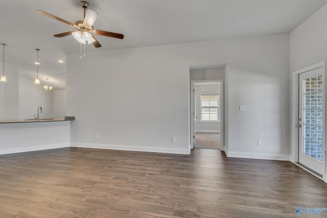 unfurnished living room featuring sink, ceiling fan with notable chandelier, and dark hardwood / wood-style floors