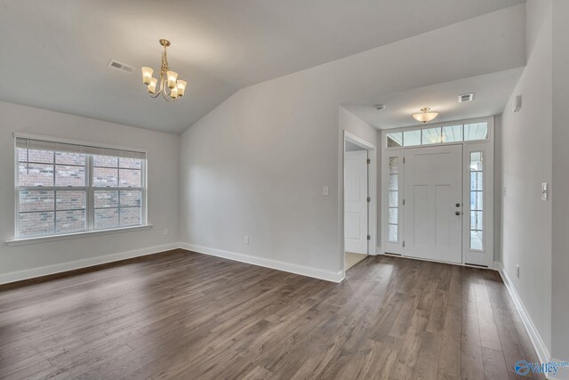 foyer featuring lofted ceiling, dark wood-type flooring, and a chandelier