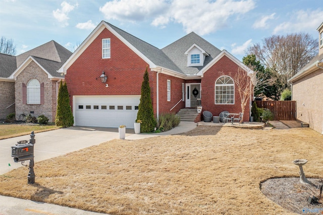 traditional-style home featuring driveway, fence, an attached garage, a shingled roof, and brick siding